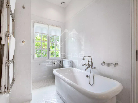 Salle de bain élégante avec baignoire sur pieds et fenêtres laissant passer la lumière naturelle.