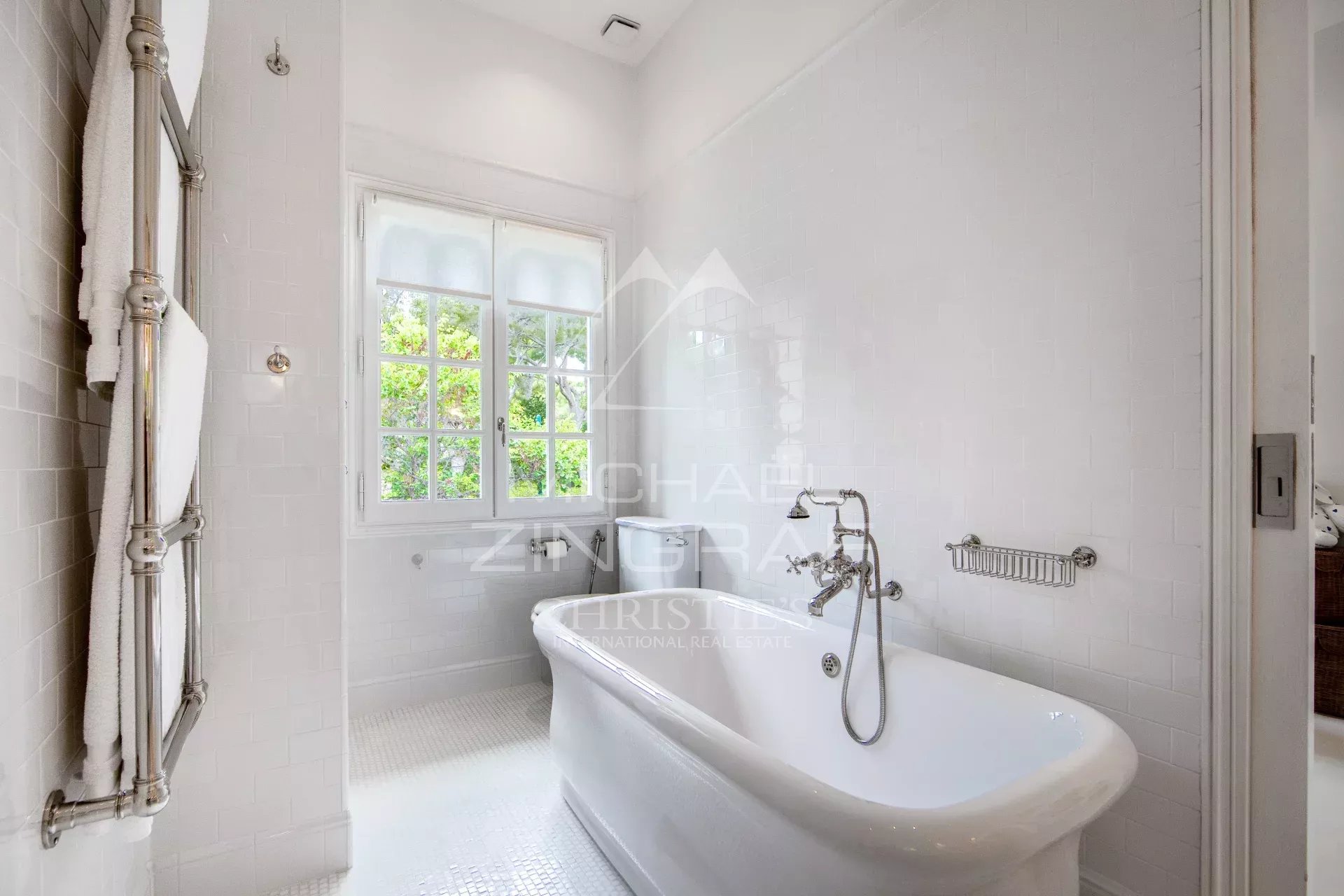Salle de bain d’un penthouse à Saint-Jean-Cap-Ferrat Salle de bain élégante avec baignoire sur pieds et fenêtres laissant passer la lumière naturelle.
