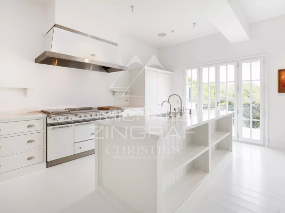 Cuisine moderne et lumineuse d'un penthouse à Saint-Jean-Cap-Ferrat, avec îlot central et équipements haut de gamme.