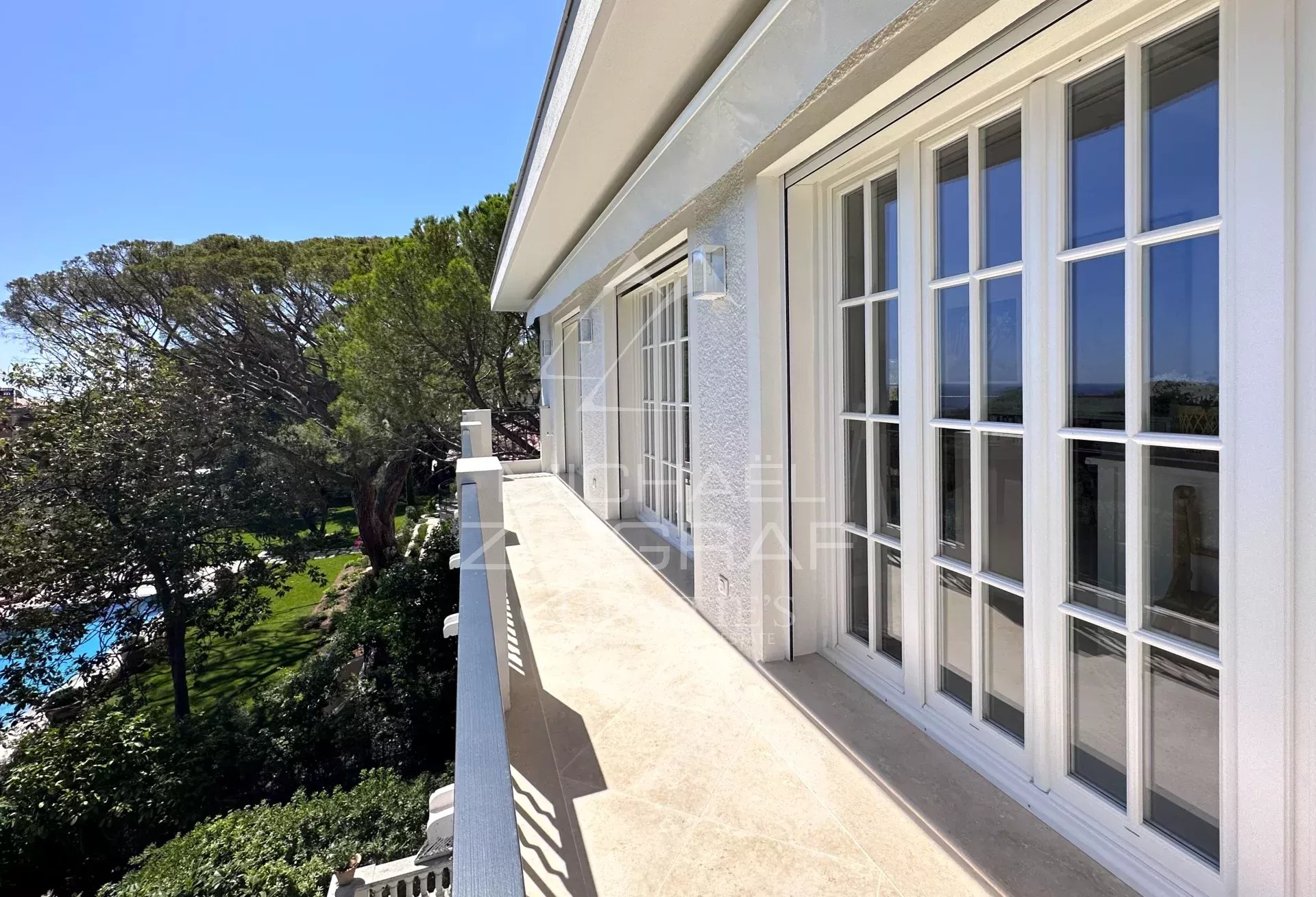 Penthouse à Saint-Jean-Cap-Ferrat Balcon d'un penthouse à Saint-Jean-Cap-Ferrat avec vue sur la mer et la végétation environnante.