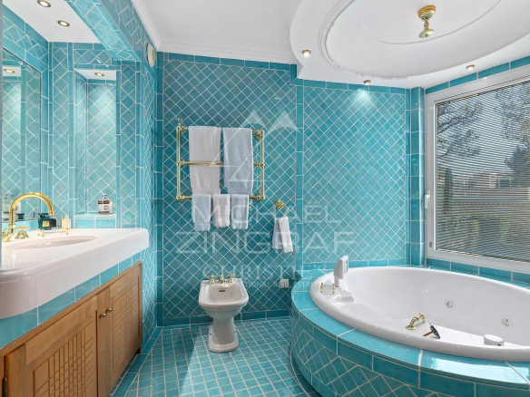 Salle de bain luxueuse avec baignoire et carrelage turquoise dans une villa contemporaine.