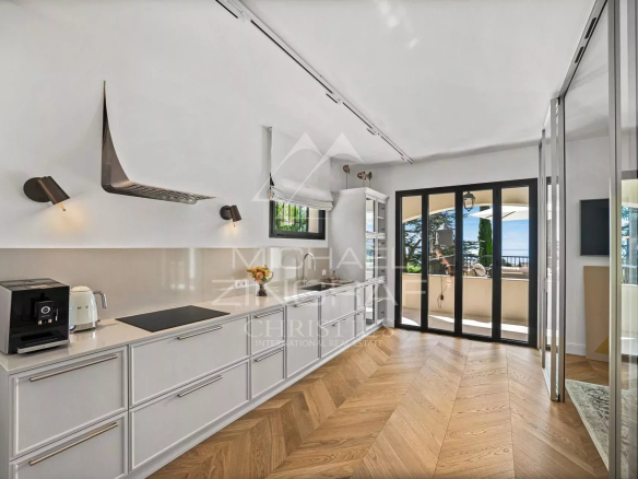 Intérieur moderne d'une villa rénovée à Roquebrune-Cap-Martin avec cuisine ouverte et accès à une terrasse.
