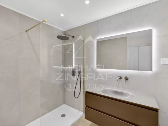 Modern bathroom with shower, sink and illuminated mirror in a renovated apartment.