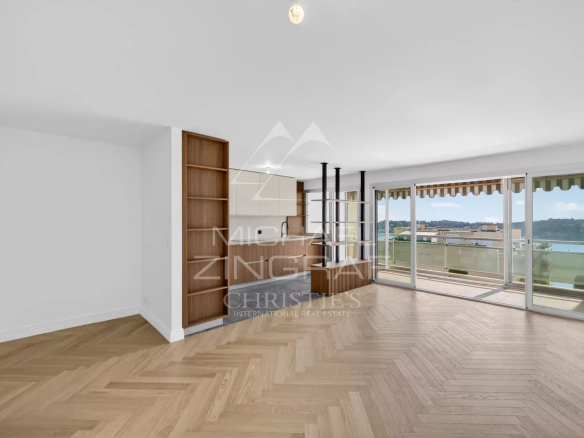 Interior of a renovated apartment with parquet flooring, large windows and a balcony in Villefranche-sur-Mer.