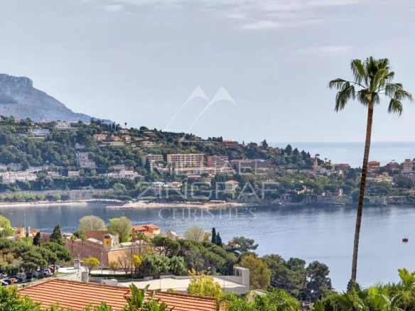 Vue panoramique de Villefranche-sur-Mer avec mer et montagnes en arrière-plan.