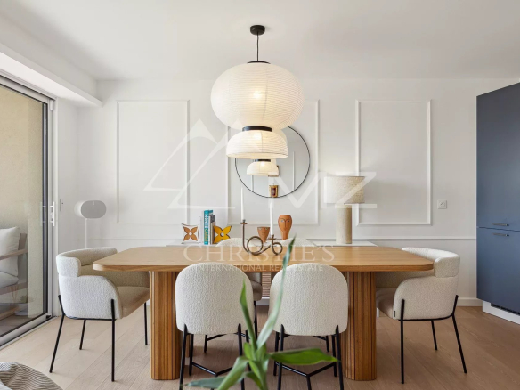 Interior of a modern apartment with a wooden dining table and white chairs.