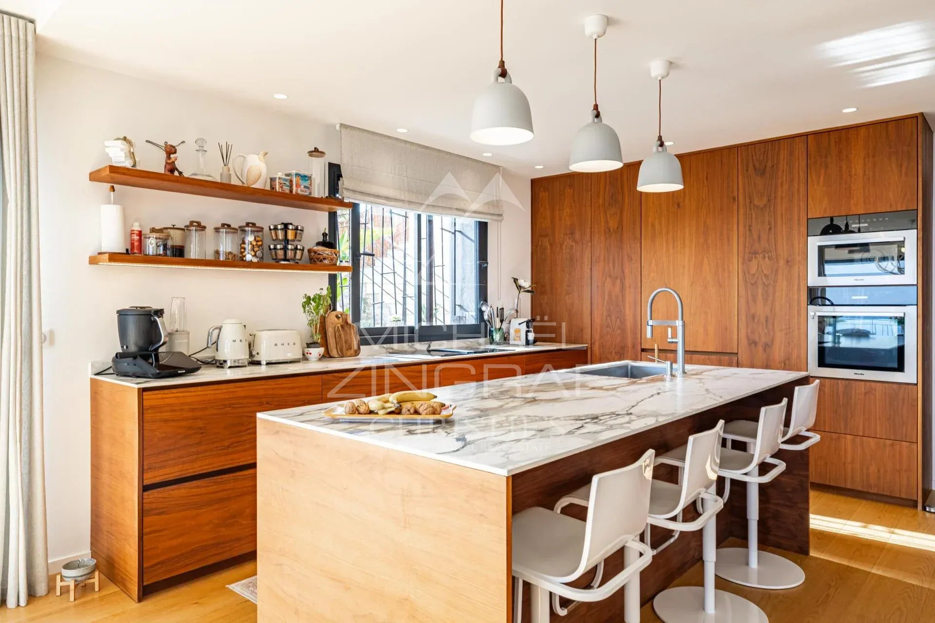 Cuisine contemporaine Cuisine moderne avec un îlot central en marbre et des rangements en bois, éclairage suspendu.