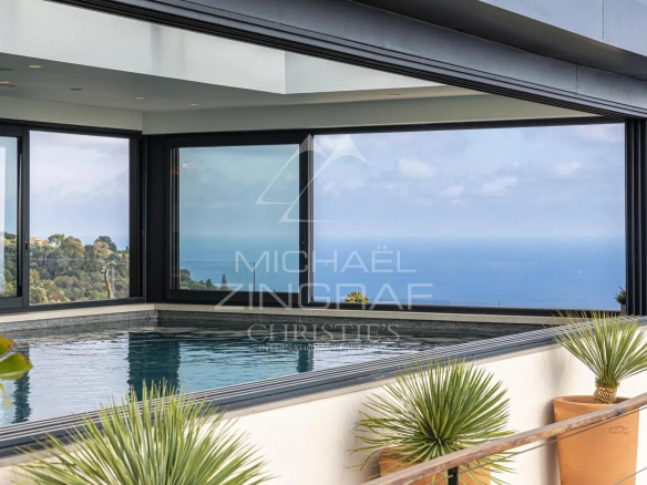 Vue intérieure d'une villa contemporaine avec piscine et vue sur la mer.