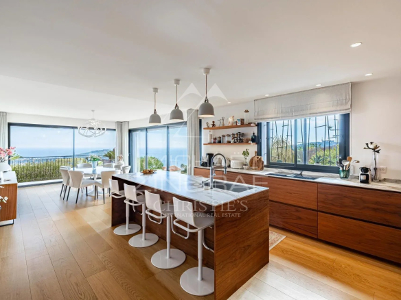 Intérieur d'une villa contemporaine avec cuisine moderne et vue sur la mer.