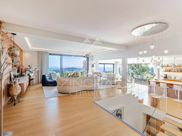 Intérieur d'une villa contemporaine avec vue sur la mer, salon spacieux et cuisine moderne.