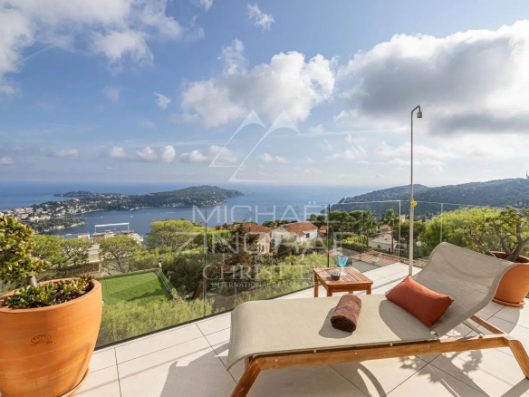 Vue panoramique sur la rade de Villefranche-sur-Mer depuis une villa contemporaine avec un transat.