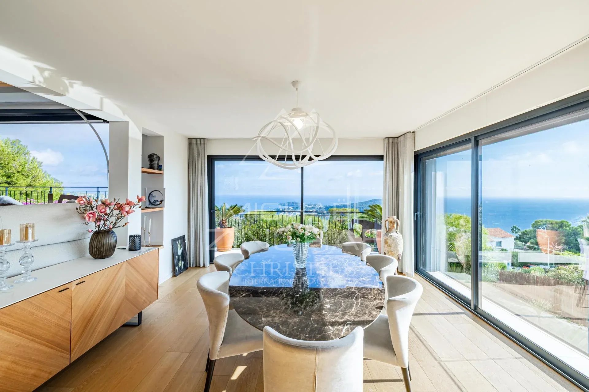 Intérieur d’une villa contemporaine à Villefranche-sur-Mer Intérieur d'une villa contemporaine avec vue sur la mer, table à manger et grandes baies vitrées.