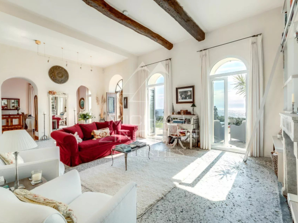 Intérieur d'une villa de style italien à Èze-sur-Mer, avec un salon lumineux et des fenêtres donnant sur la mer.