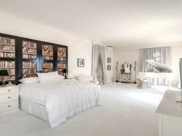 Chambre spacieuse avec lit, bibliothèque murale et piano à Èze-sur-Mer.