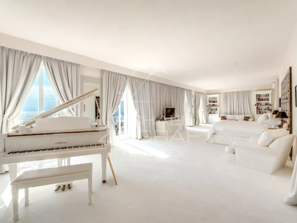 Intérieur d'une villa de style italien à Èze-sur-Mer, avec un piano blanc et des fenêtres donnant sur la mer.