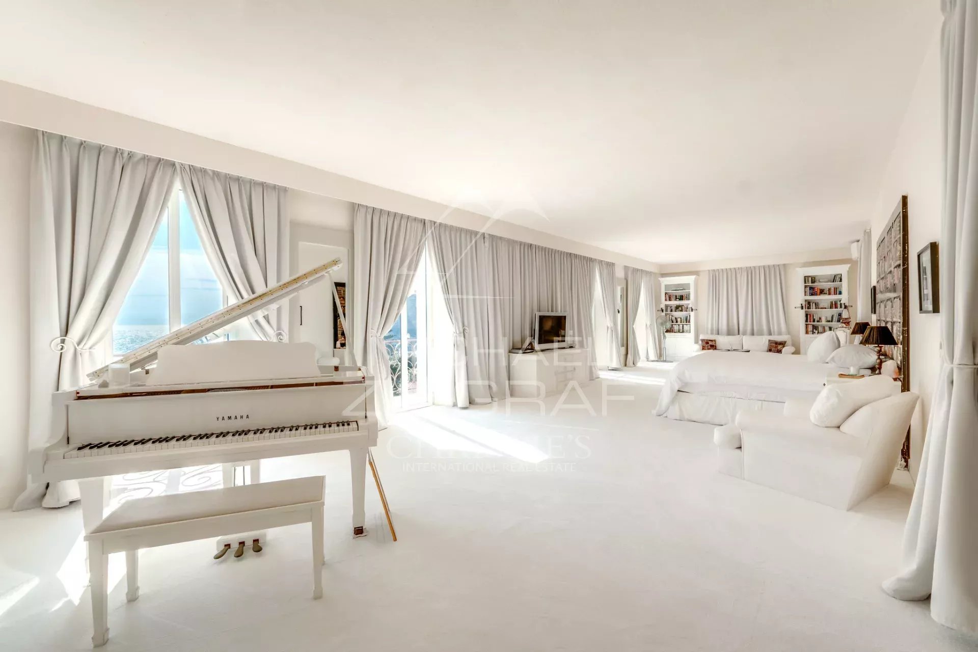 Intérieur d’une villa à Èze-sur-Mer Intérieur d'une villa de style italien à Èze-sur-Mer, avec un piano blanc et des fenêtres donnant sur la mer.
