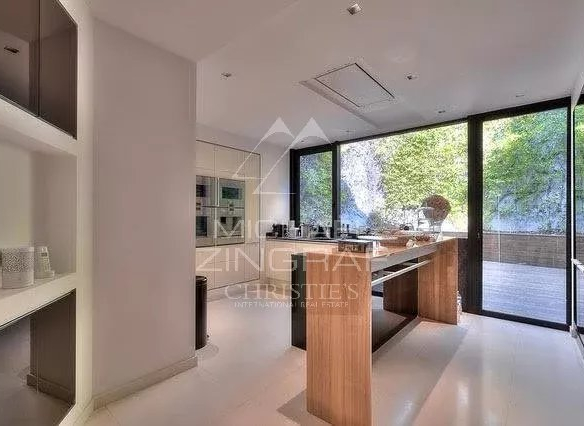 Intérieur d'une villa contemporaine avec cuisine moderne et grandes fenêtres donnant sur un espace extérieur.
