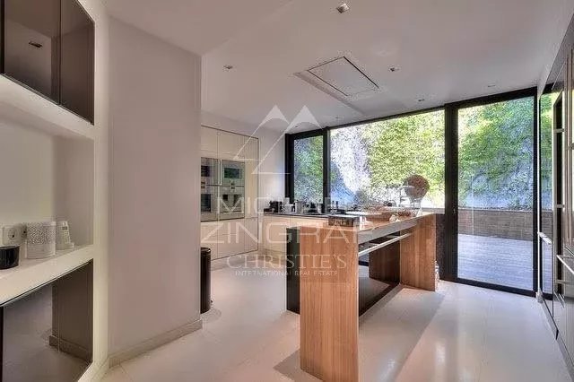 Intérieur d'une villa contemporaine avec cuisine moderne et grandes fenêtres donnant sur un espace extérieur.