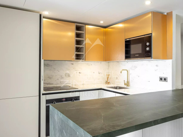 Cuisine moderne avec des éléments dorés et un plan de travail en marbre dans un appartement à Beausoleil.