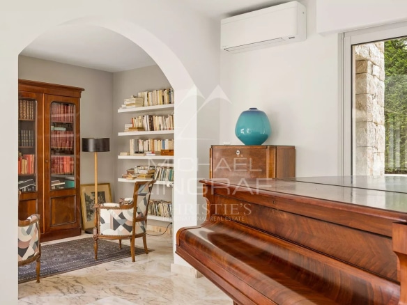 Intérieur d'une villa au Cap d'Antibes avec un piano, des étagères et un coin lecture