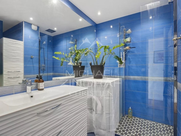 Modern bathroom with blue tiles and potted plants.