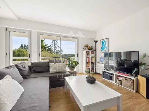 Bright living room of a modern apartment with sofa and television, view of nature.