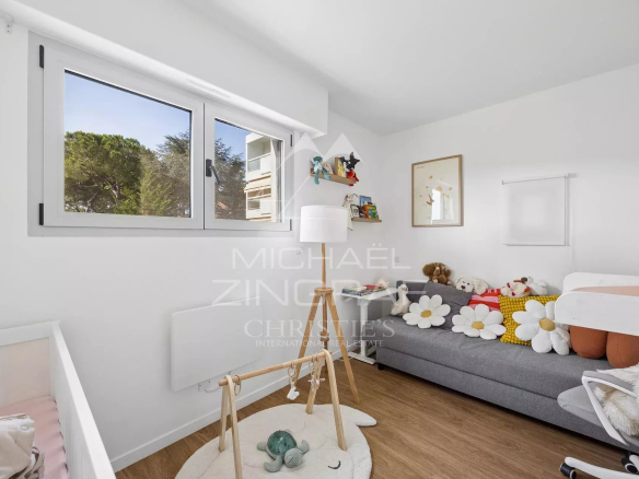 Bedroom in a modern apartment with a sofa, toys and a window overlooking a park.
