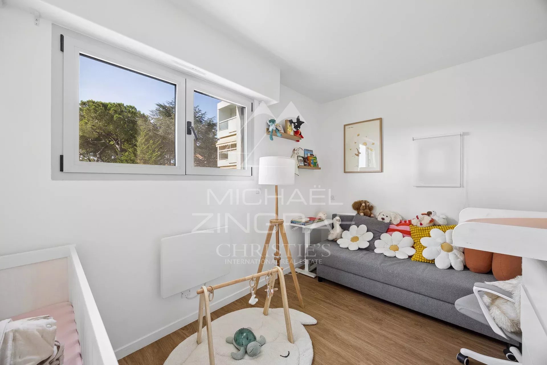 Bright bedroom in an apartment in Cap d'Antibes Bedroom in a modern apartment with a sofa, toys and a window overlooking a park.