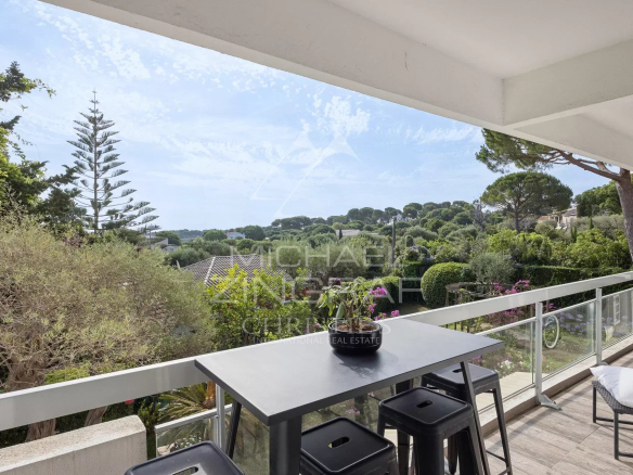 View from a balcony of an apartment with a table and chairs, surrounded by greenery in Cap d'Antibes.