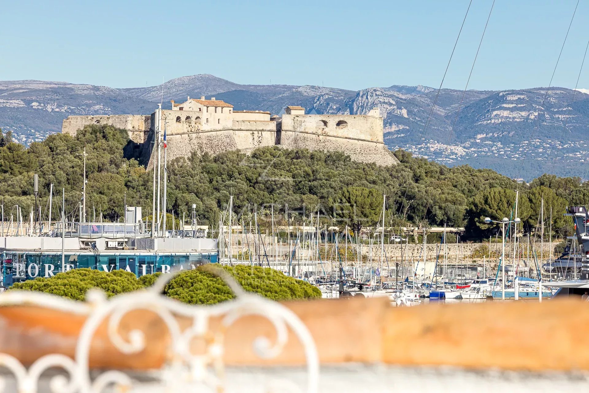 Vue panoramique sur le château et le port d'Antibes depuis une terrasse.