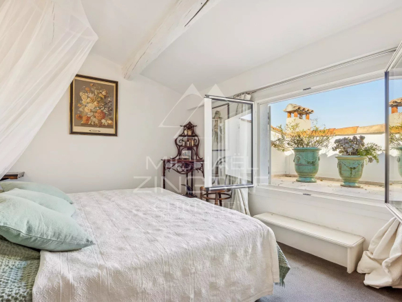 Chambre d'un appartement avec fenêtres ouvertes sur une vue extérieure, décorée de plantes