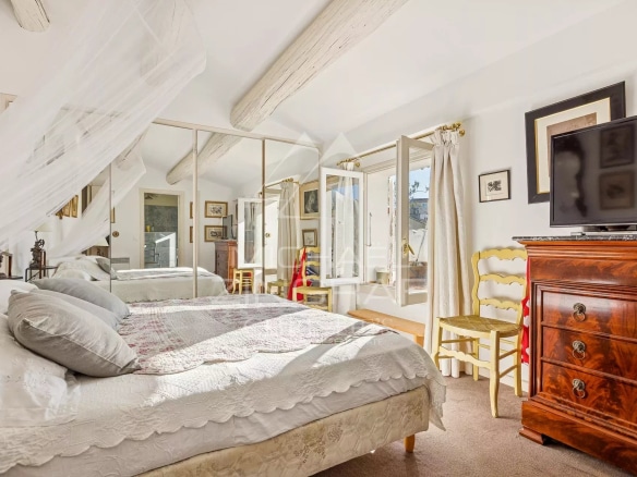 Chambre d'un appartement au dernier étage avec vue sur la ville, décorée avec des meubles anciens.