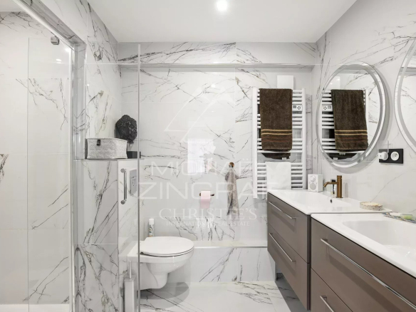 Salle de bain moderne avec carrelage marbré et équipements haut de gamme.