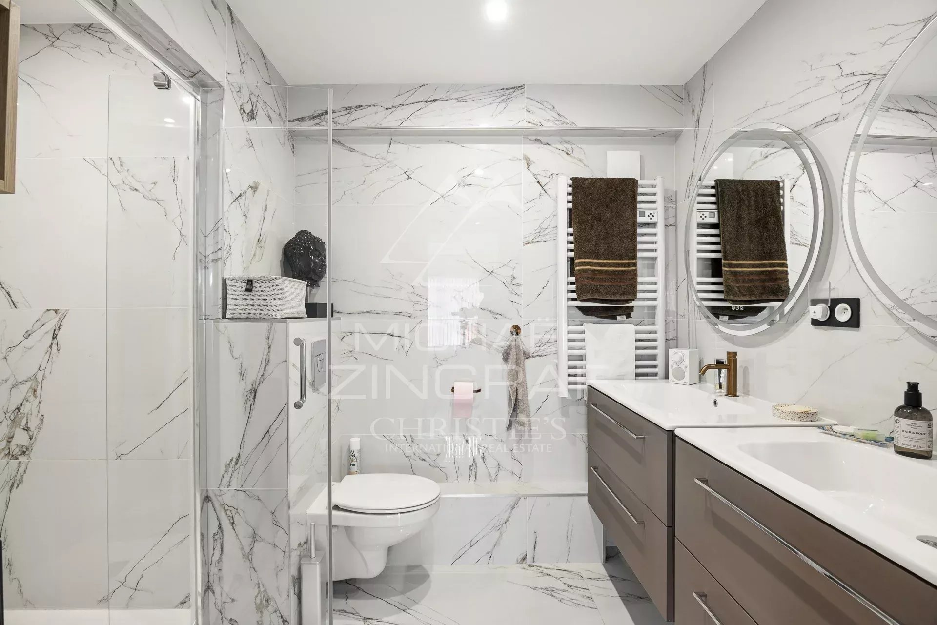 Salle de bain moderne avec carrelage marbré et équipements haut de gamme.