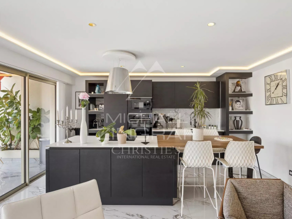 Cuisine moderne et lumineuse d'un appartement rénové à Antibes, avec un bar et un accès à un balcon.