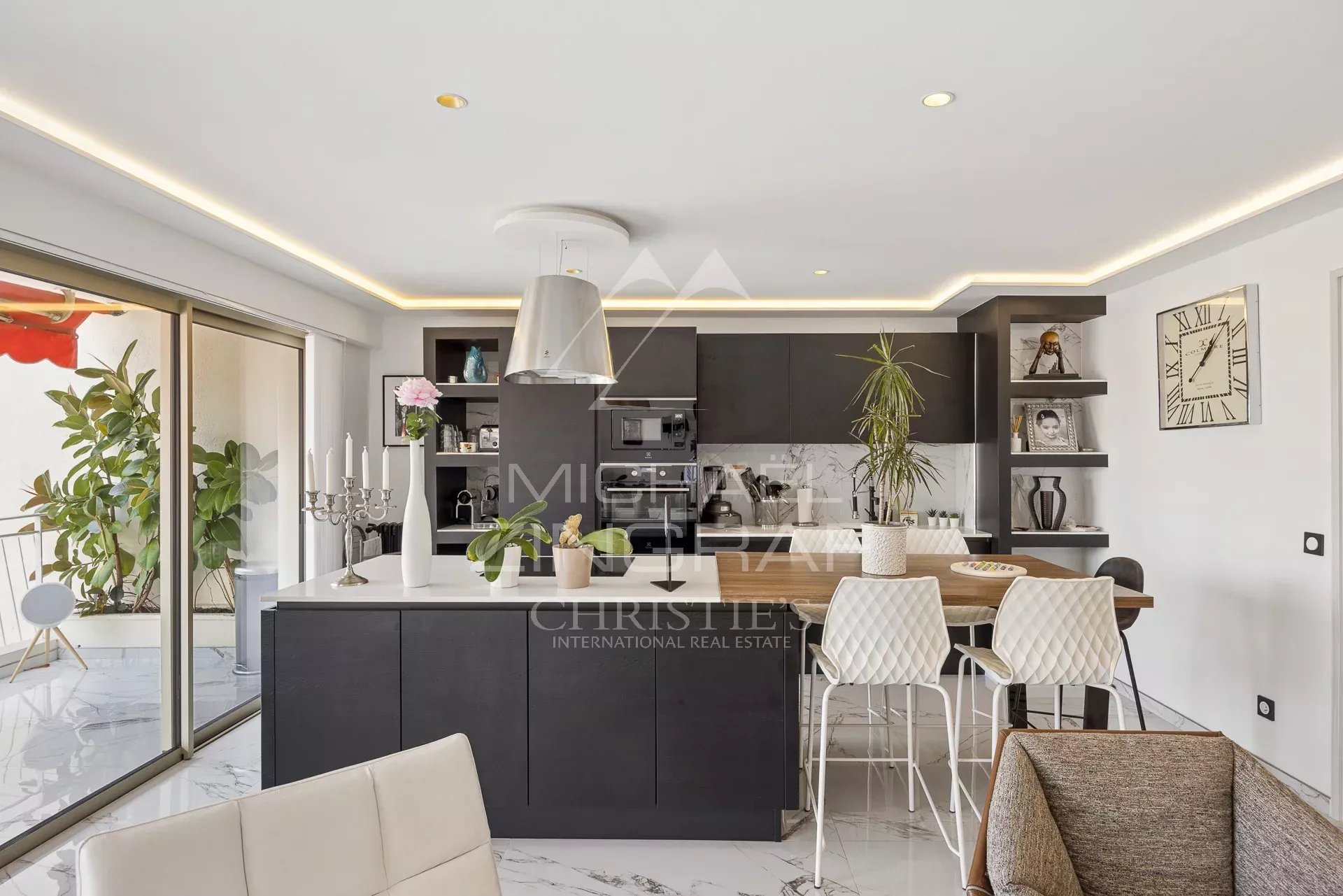 Cuisine moderne et lumineuse d'un appartement rénové à Antibes, avec un bar et un accès à un balcon.