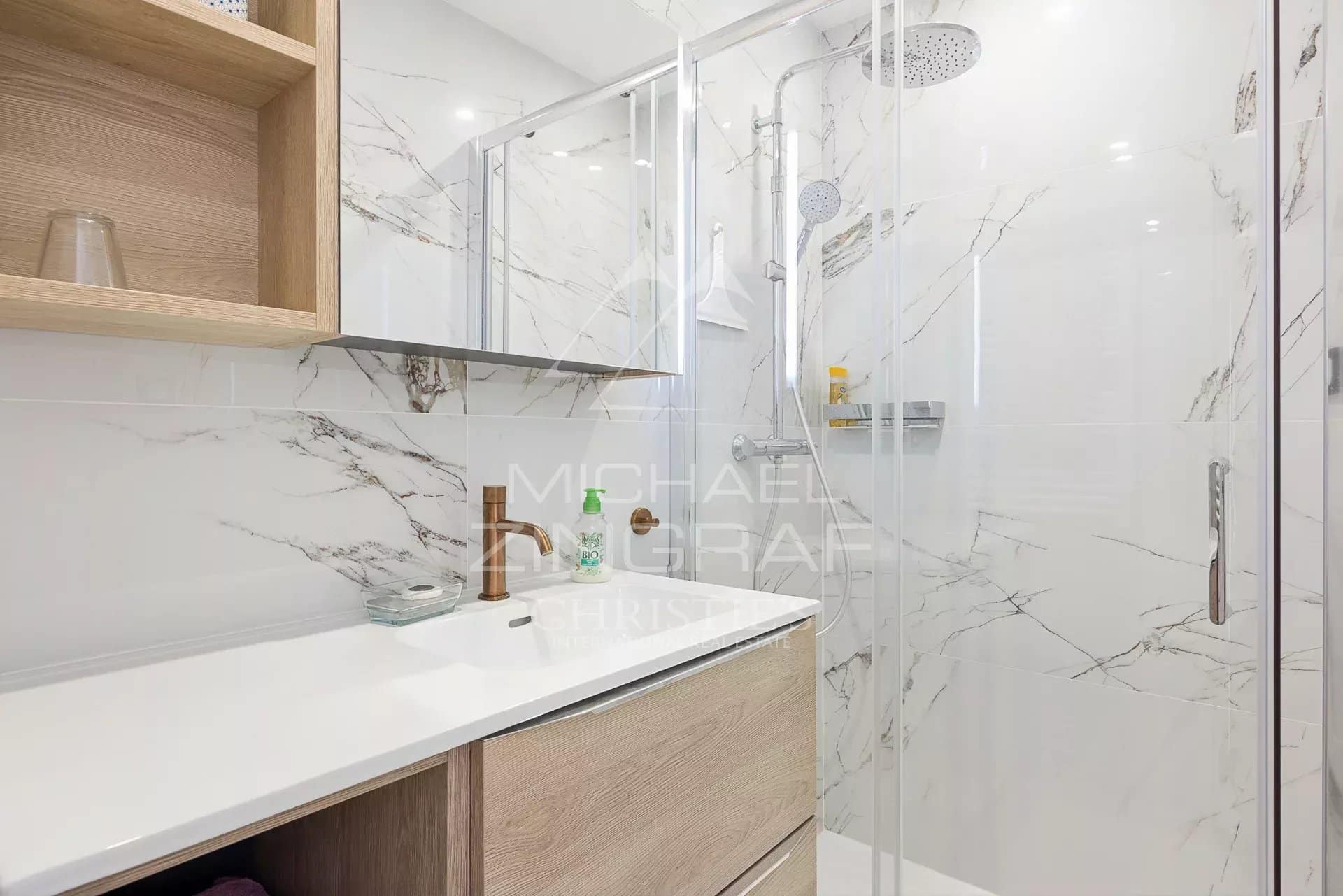 Salle de bain moderne avec douche en verre et meuble en bois clair.