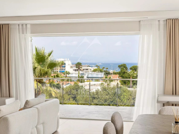 View from inside a contemporary villa with a balcony overlooking a green landscape and the sea.
