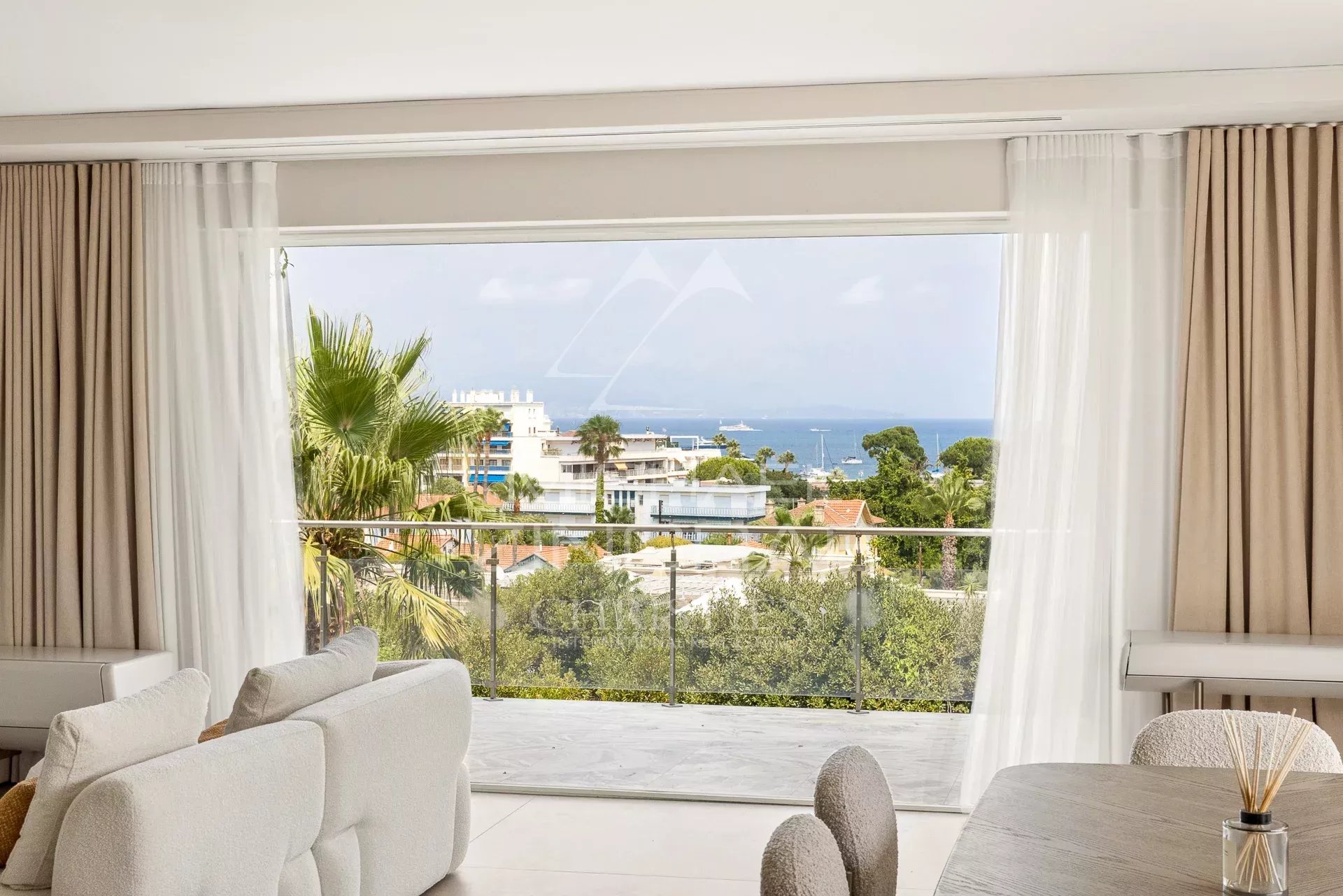 View from inside a contemporary villa with a balcony overlooking a green landscape and the sea.