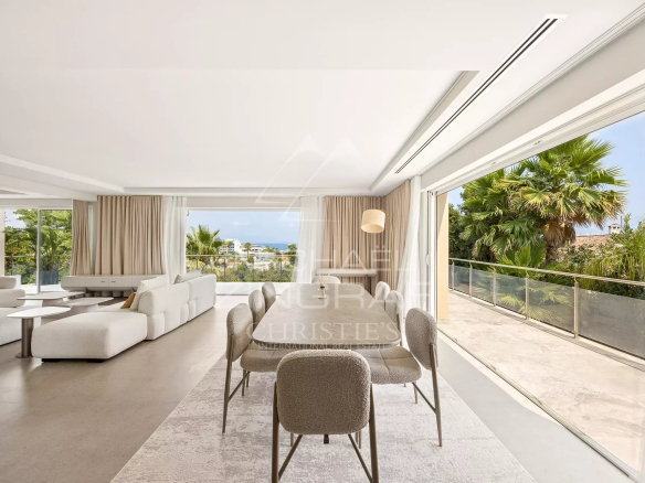 Interior of a renovated contemporary villa with living room and dining room, garden view.