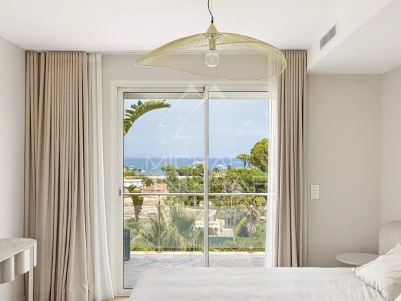 Bright room with sea view and access to a balcony, decorated with light curtains.