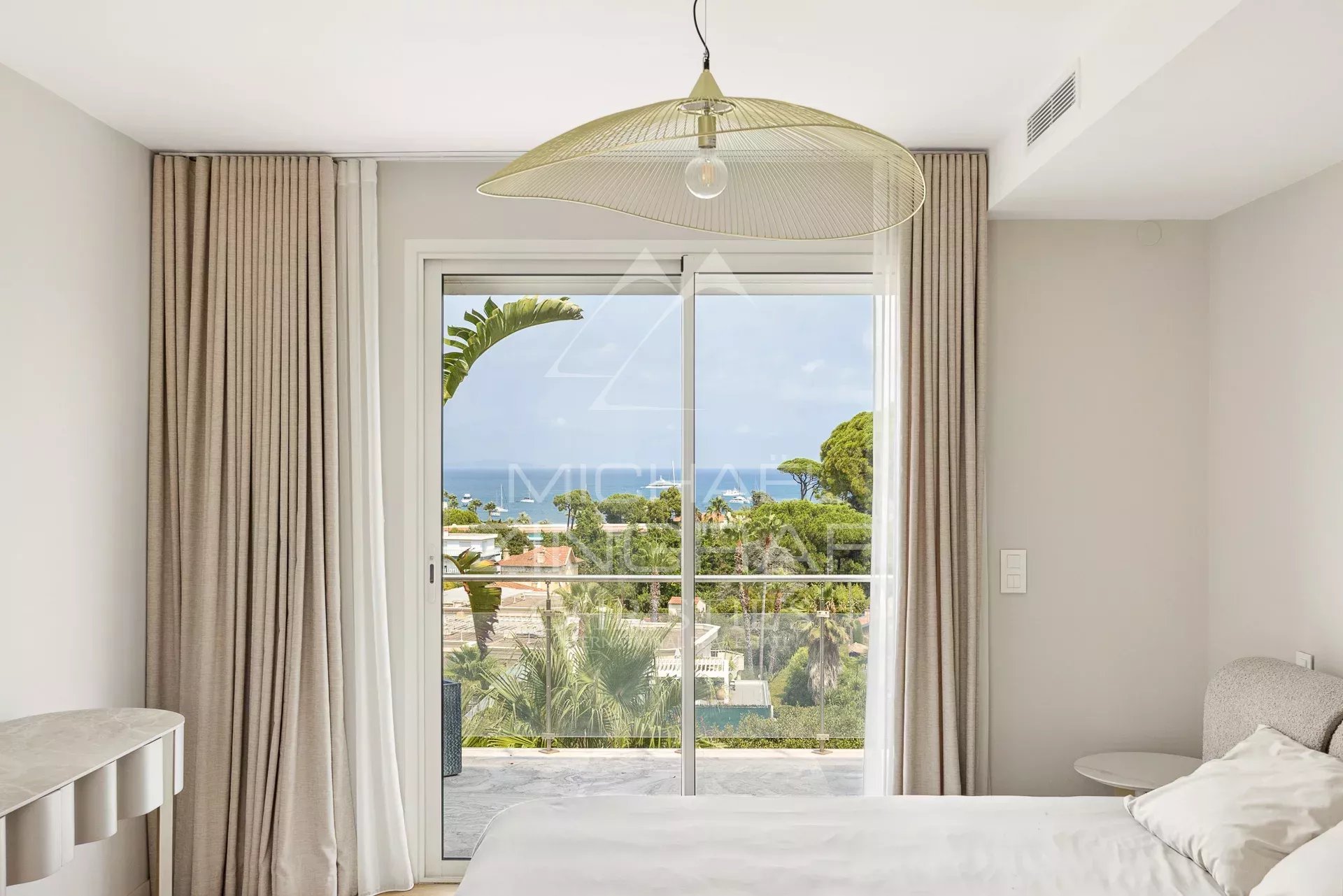 Bright room with sea view and access to a balcony, decorated with light curtains.
