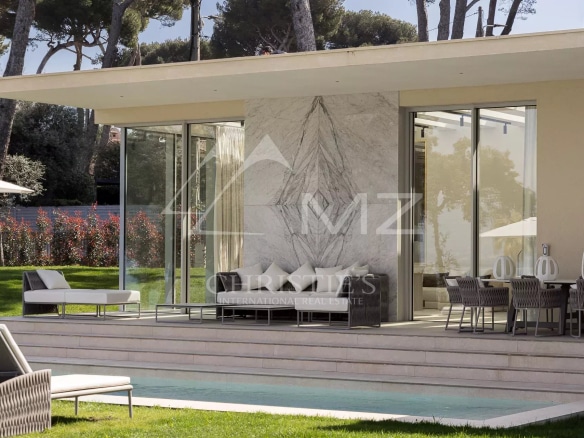 Modern villa with large bay windows and swimming pool, surrounded by greenery in Cap d'Antibes.