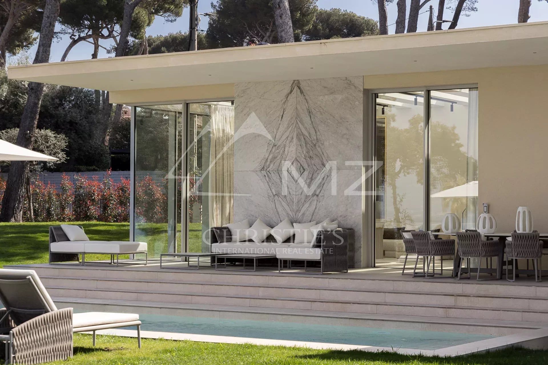 Villa moderne avec grandes baies vitrées et piscine, entourée de verdure à Cap d'Antibes.