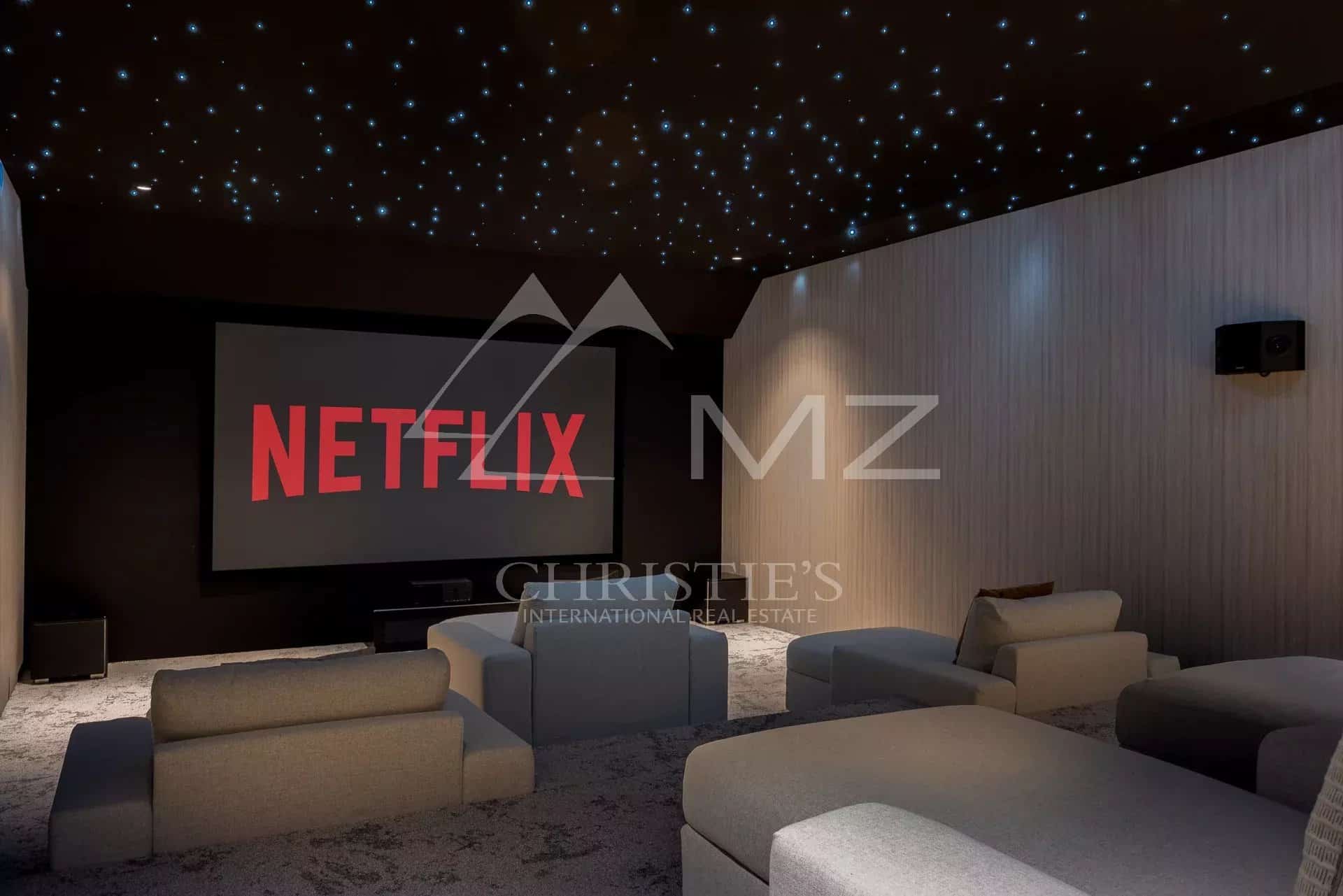 Salle de cinéma avec écran de projection et canapés confortables.