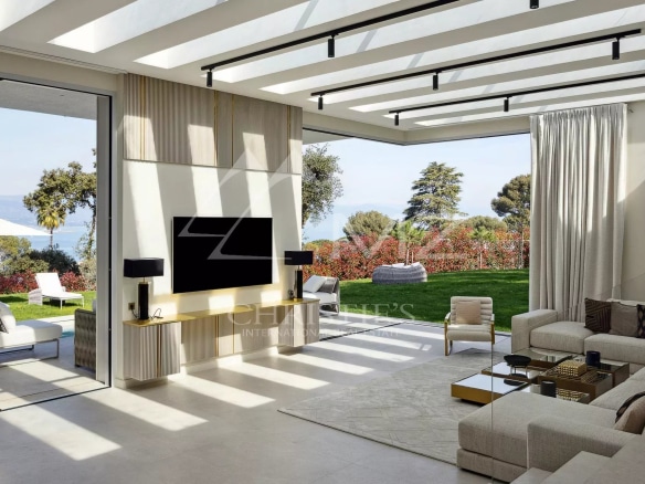 Interior of a modern villa with a bright living room and a view of a flower garden in Antibes.