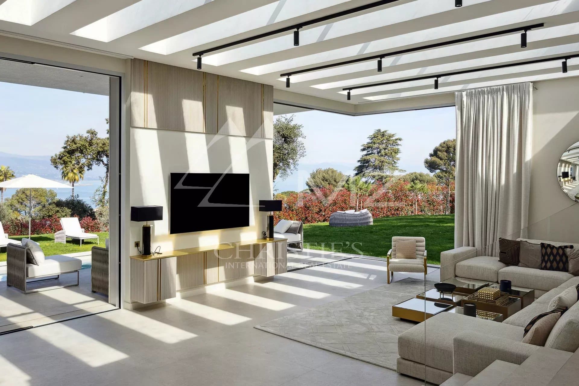 Intérieur d'une villa moderne avec salon lumineux et vue sur un jardin fleuri à Antibes.
