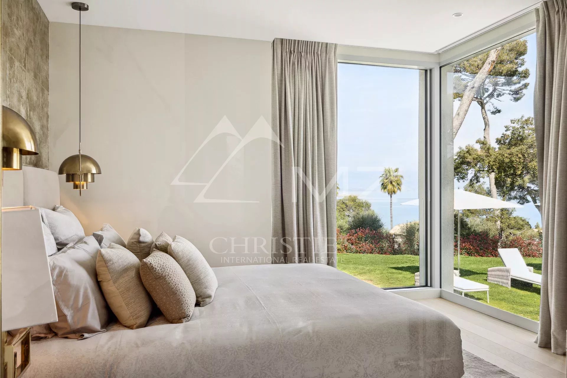 Chambre d'une villa moderne avec vue sur la mer à Antibes, fenêtres larges et décoration élégante.