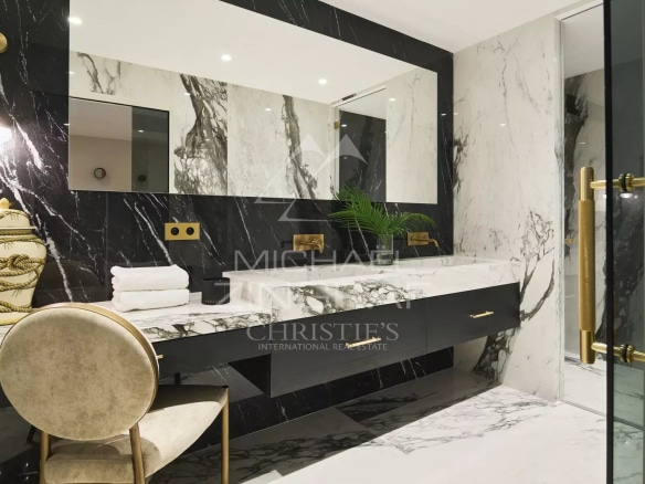 Salle de bain moderne avec marbre noir et blanc, miroir et mobilier élégant.