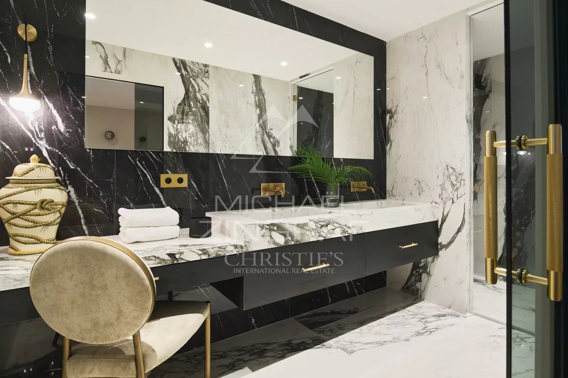 Salle de bain moderne avec marbre noir et blanc, miroir et mobilier élégant.